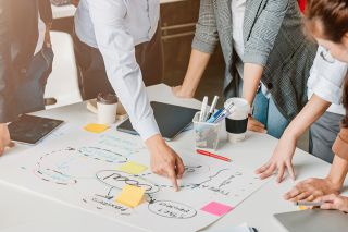 © whyframeshot - stock.adobe.com Foto: Personen diskutieren eine Flipchart